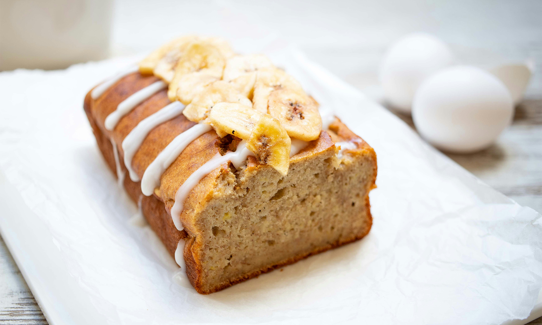 A loaf of banana bread with fresh banas on top.