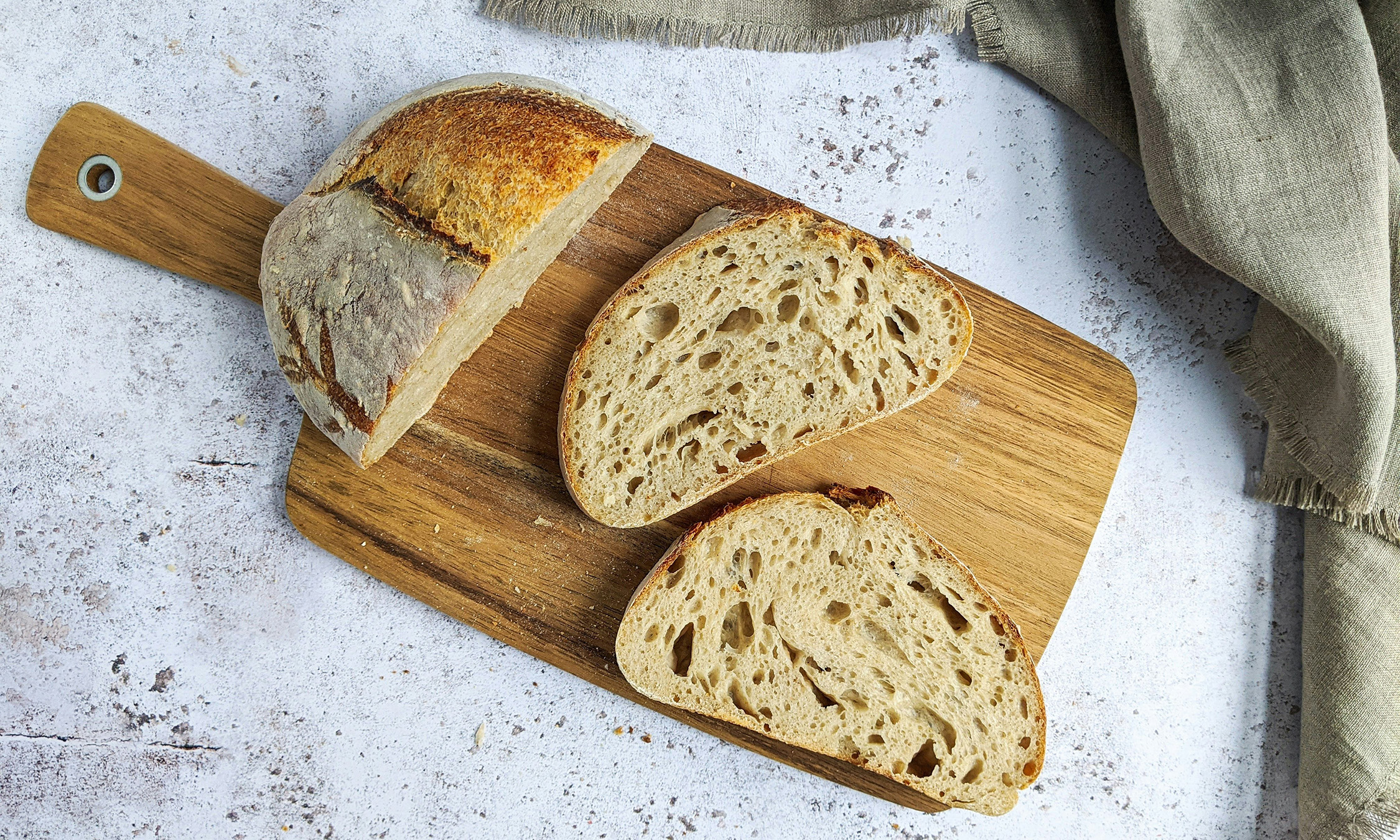 Part of a loaf of bread and two slices of bread on a wooden cutting board.