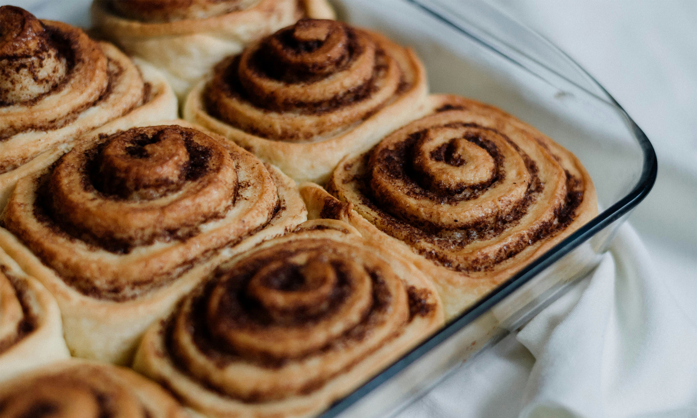 A clear glass dish filled with cinnamon rolls.