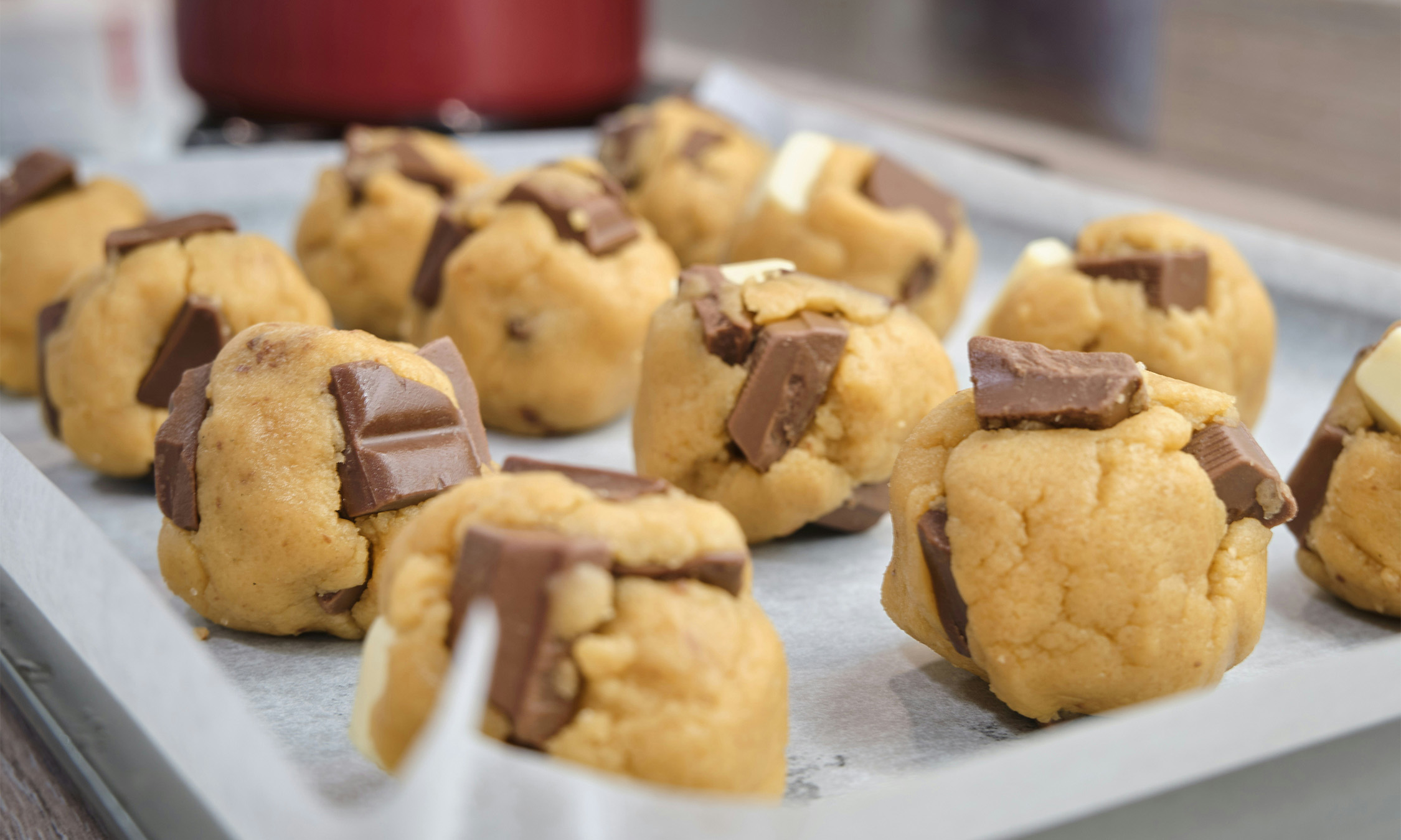 Some chocolate chip cookie dough balls on a baking tray.
