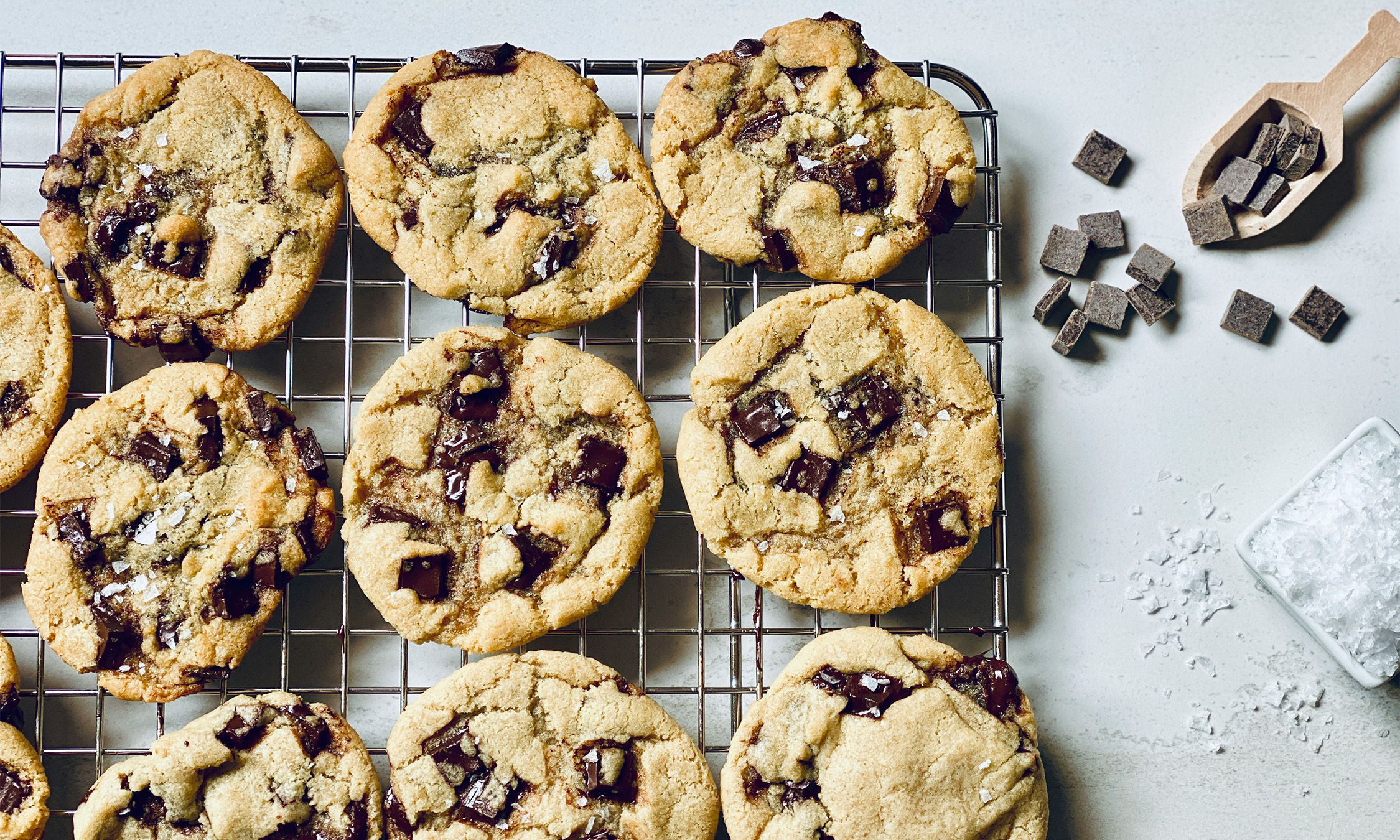 Some chocolate chip cookies are layed out on a drying rack.