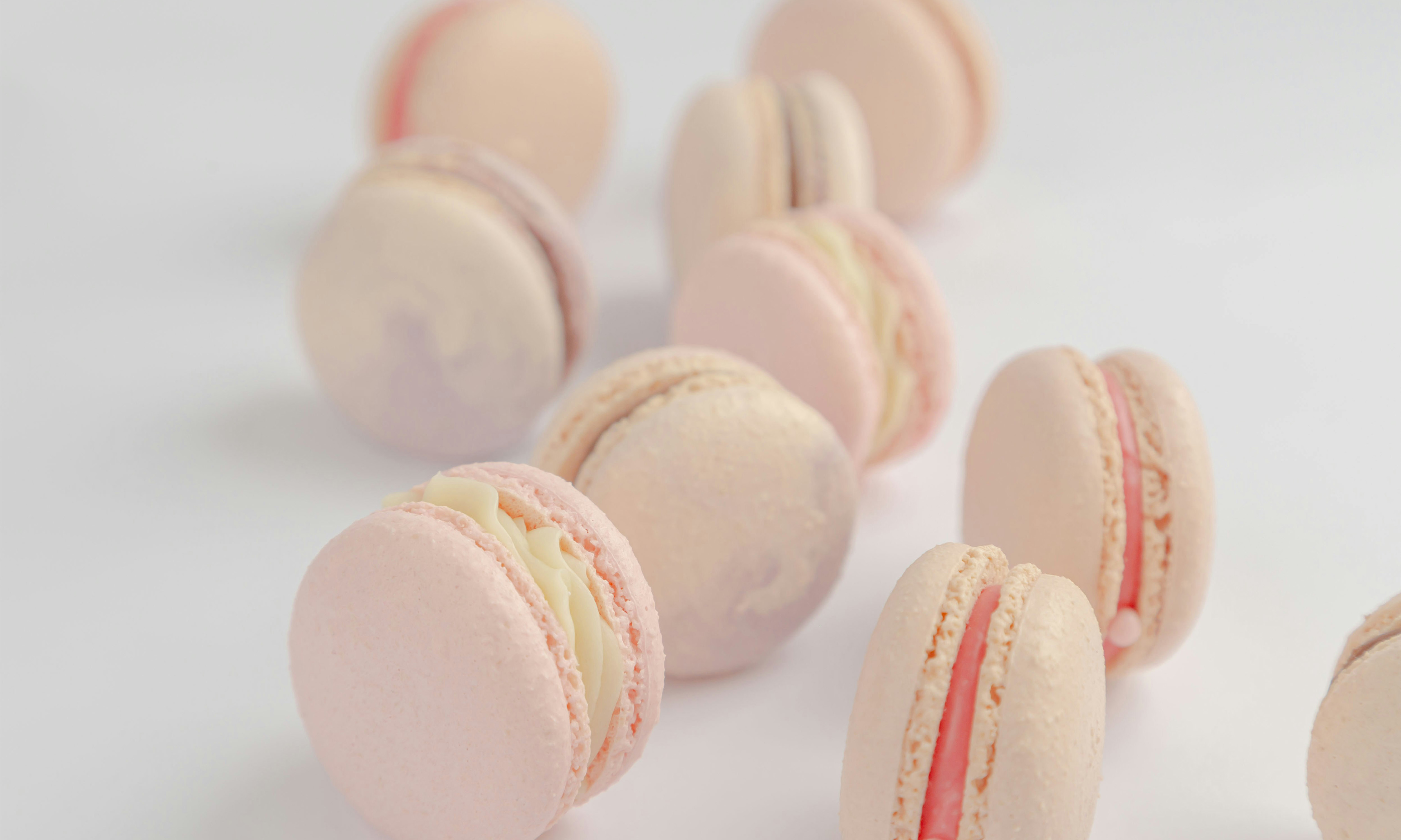 Nine macarons standing on their side arranged in a zig zag shape on a white surface.