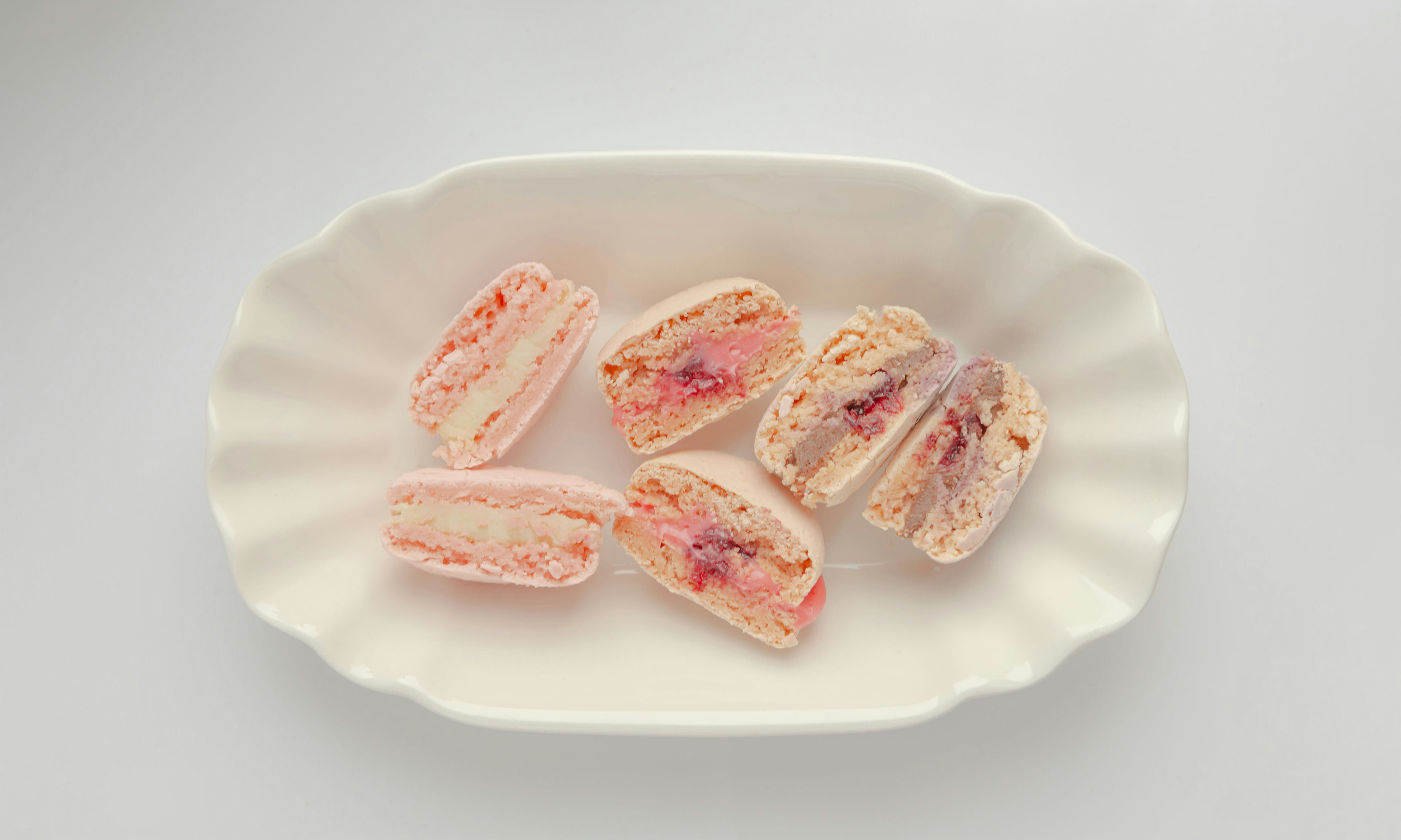 Three macarons cut in half on a white plate.