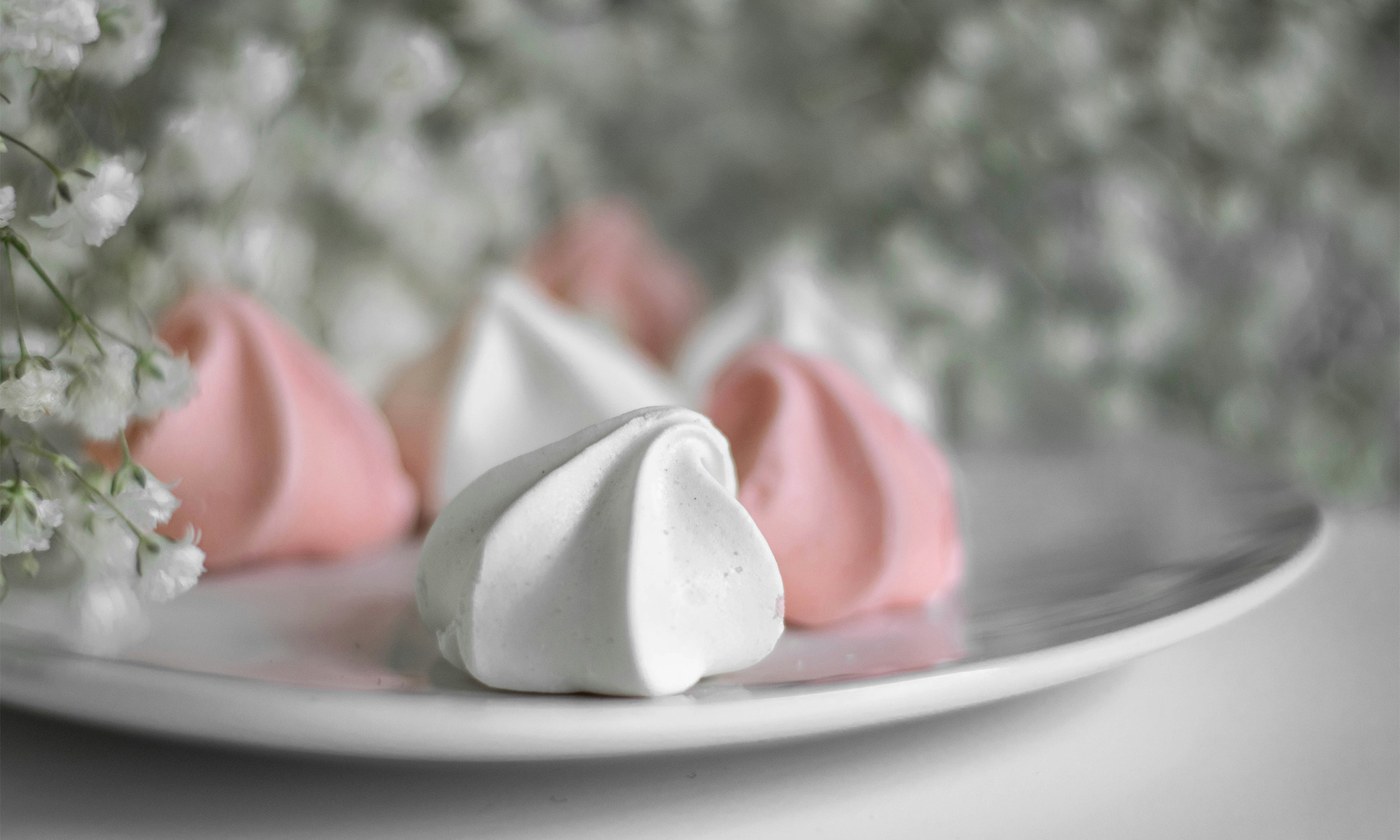 A white plate with a couple of white and pink meringues.